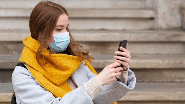 Foto grátis mulher com máscara médica tirando fotos com smartphone
