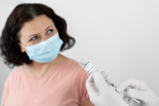 Mulher com máscara médica tomando vacina