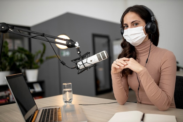 Mulher com máscara médica transmitindo rádio com microfone