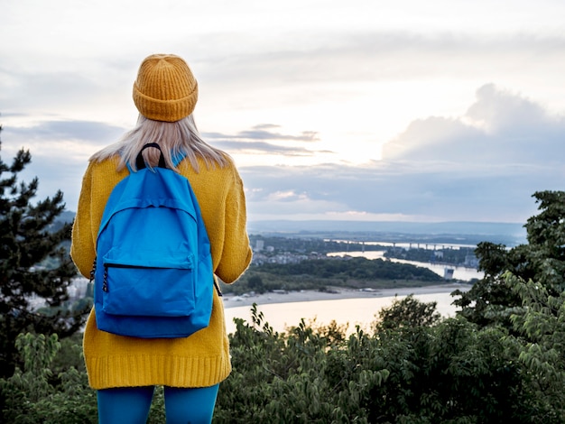 Mulher com mochila, admirando a vista para a montanha