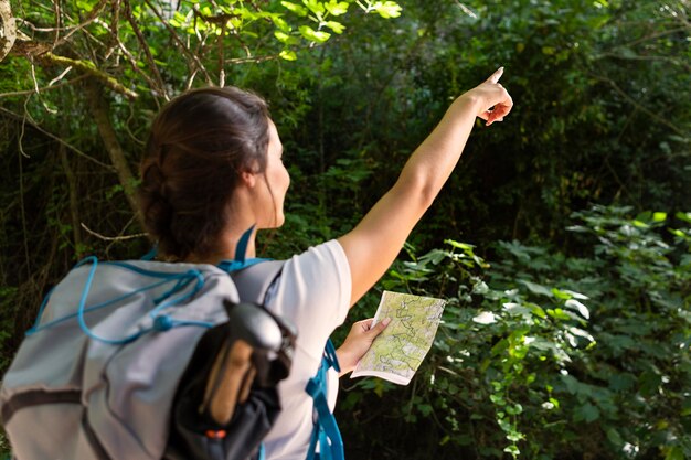 Mulher com mochila apontando enquanto segura o mapa