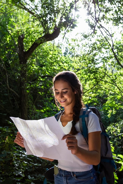 Mulher com mochila explorando a natureza enquanto olha o mapa