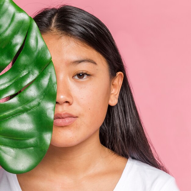 Mulher, com, monstera, folha, olhando câmera