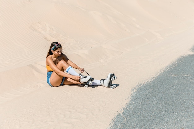 Mulher, com, patins, sentando areia