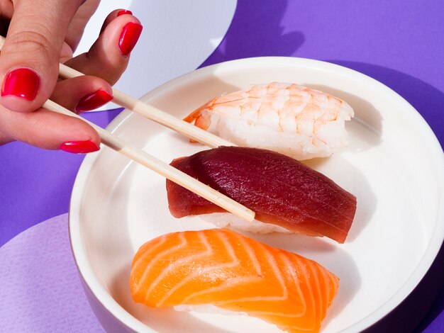 Mulher com pauzinhos tomando uma placa de forma de sushi de atum