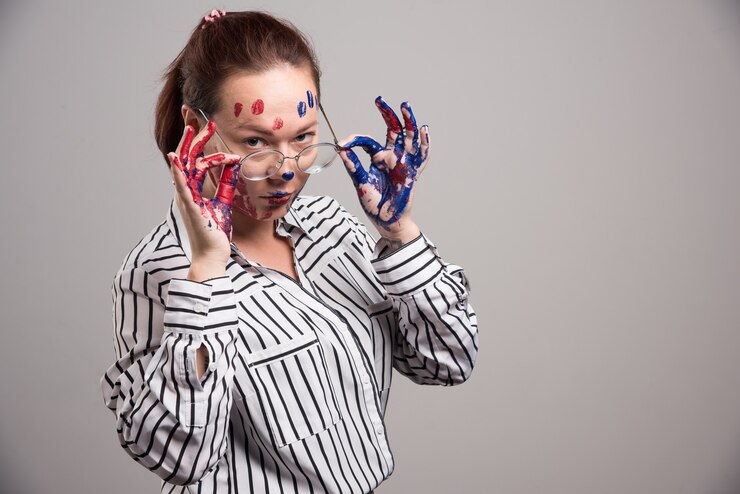 Foto grátis mulher com pinturas no rosto coloca óculos em fundo cinza