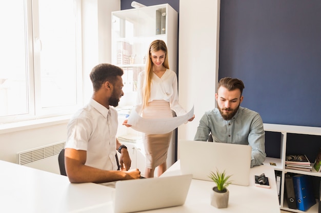 Mulher com projecto perto de colegas de trabalho