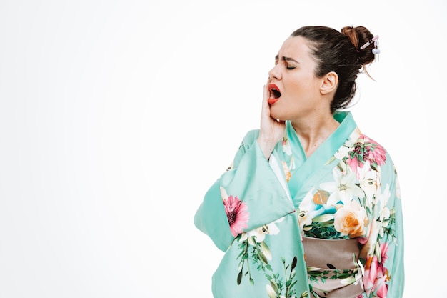 Mulher com quimono japonês tradicional não se sentindo bem tocando a bochecha e sentindo dor de dente no branco