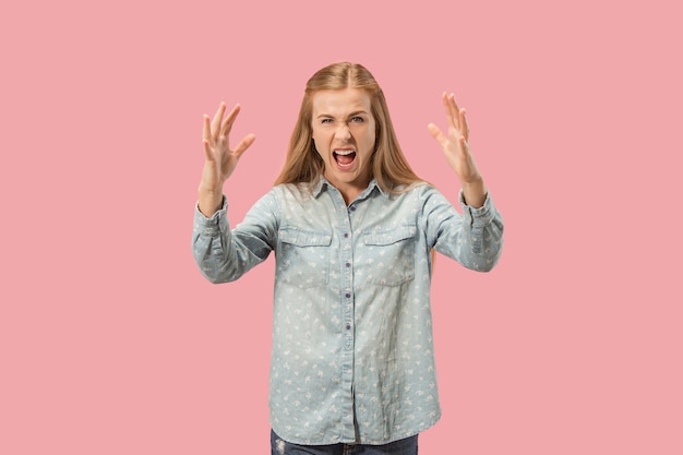 Mulher com raiva, olhando para a câmera. Mulher de negócios agressivo em pé isolado no fundo do estúdio rosa na moda. Retrato feminino de meio corpo.