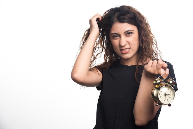 Mulher com raiva segurando o cabelo e o relógio no fundo branco. Foto de alta qualidade