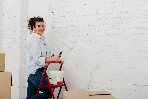 Mulher com rolo de pintura olhando a câmera