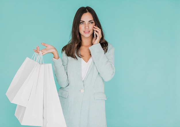 Mulher com sacos de compras, falando ao telefone