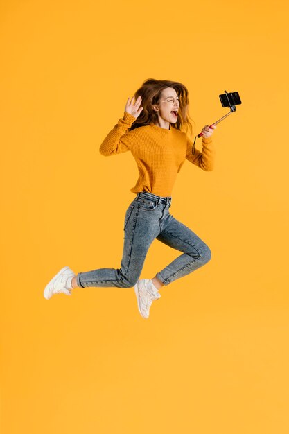 Mulher com selfie stick pulando