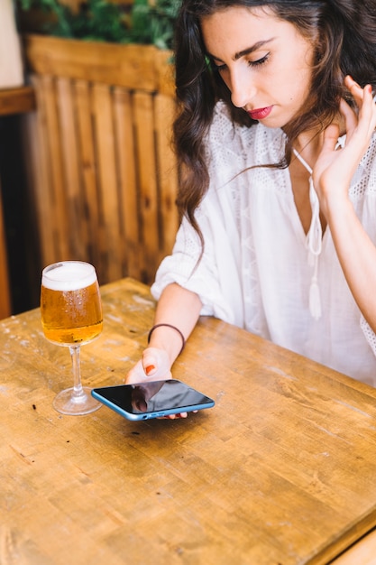 Mulher com smartphone e cerveja