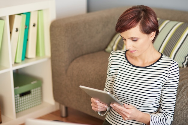 Mulher com tablet digital ao lado do sofá