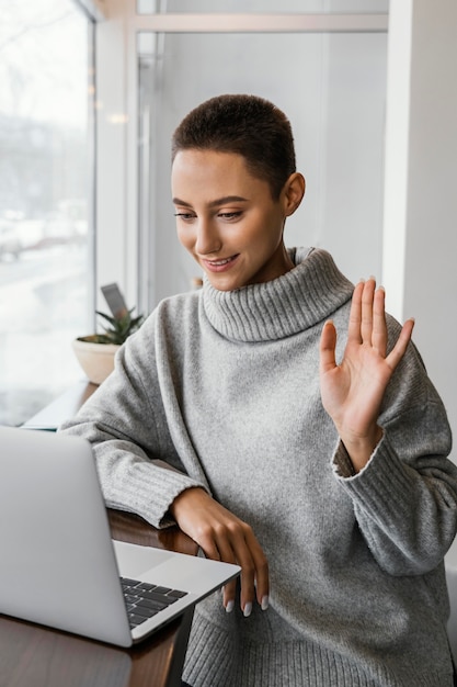 Foto grátis mulher com tiro médio acenando para um laptop