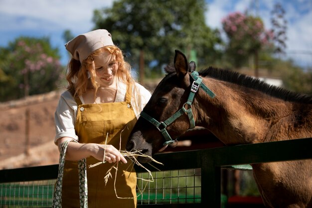 Mulher com tiro médio alimentando cavalo