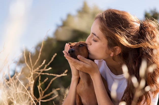 Mulher com tiro médio beijando cachorro