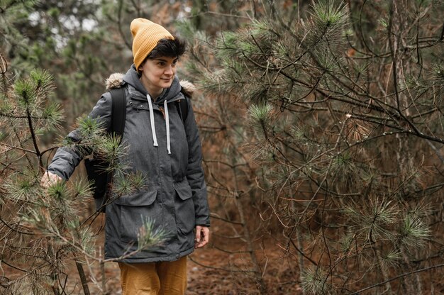 Mulher com tiro médio caminhando na floresta