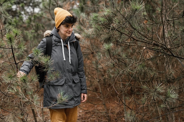 Mulher com tiro médio caminhando na floresta