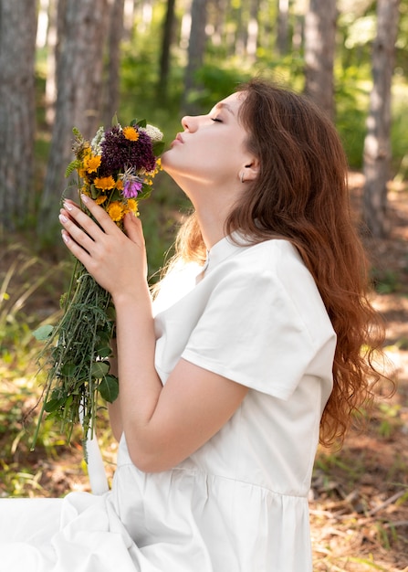 Mulher com tiro médio cheirando flores