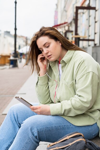 Mulher com tiro médio colocando fones de ouvido