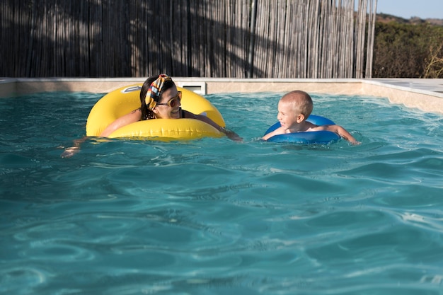 Mulher com tiro médio e criança na piscina