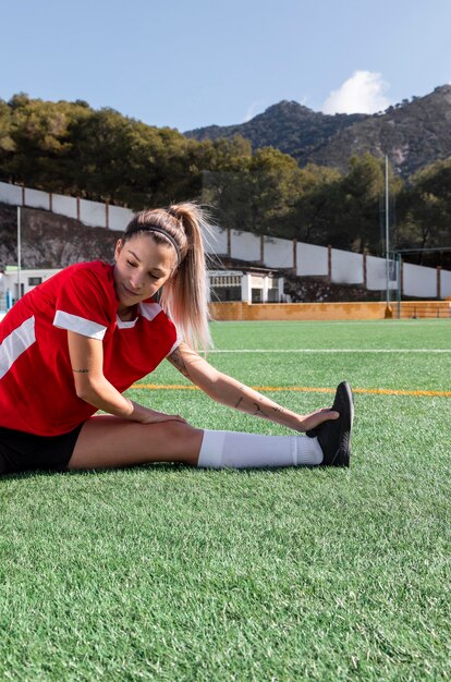 Mulher com tiro médio esticando a perna no campo