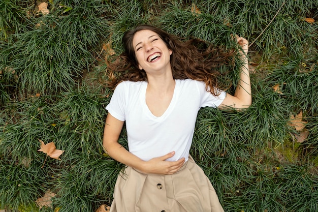 Mulher com tiro médio rindo na grama