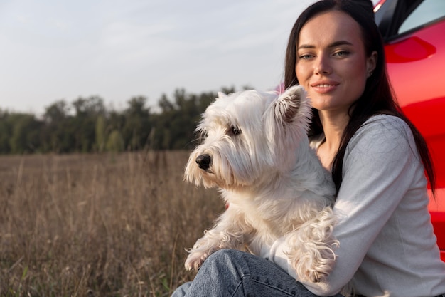 Mulher com tiro médio segurando cachorro ao ar livre