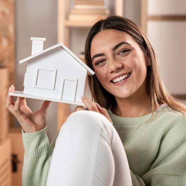 Mulher com tiro médio segurando uma pequena casa