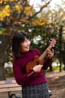 Foto grátis mulher com tiro médio tocando ukulele