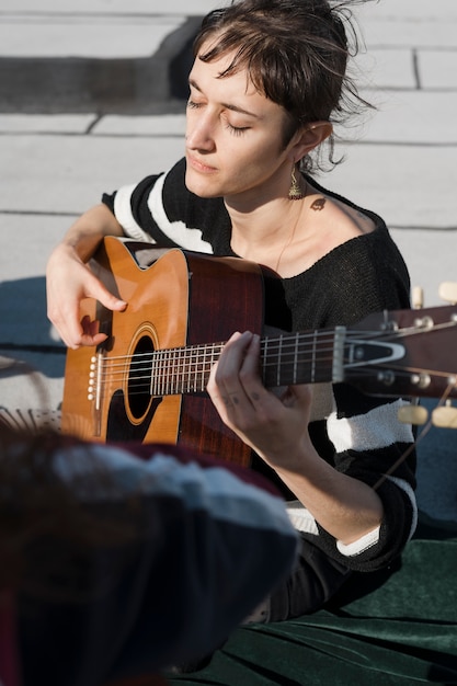 Mulher com tiro médio tocando violão