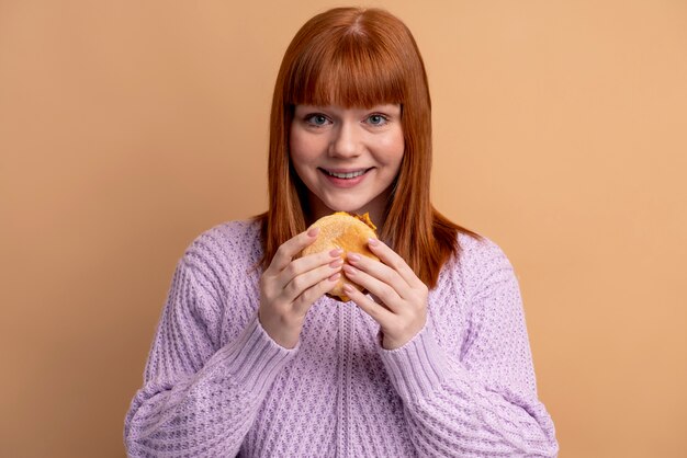 Mulher com transtorno alimentar tentando comer hambúrguer