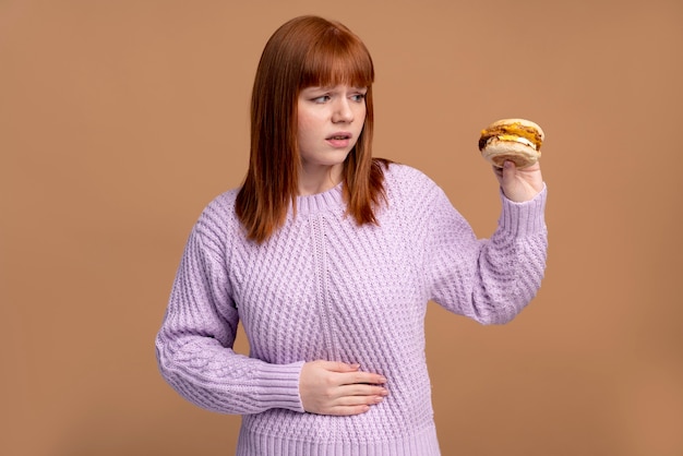 Mulher com transtorno alimentar tentando comer hambúrguer