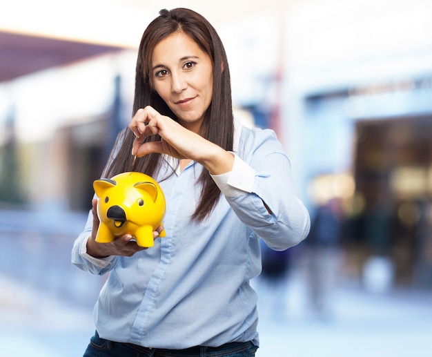 Mulher com um banco piggy porco amarelo