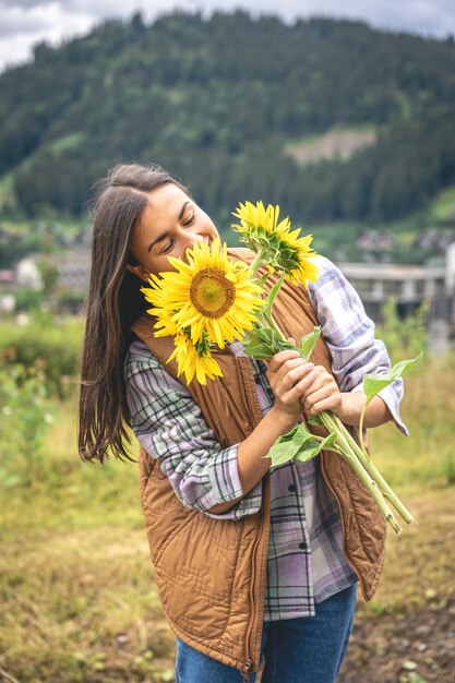 Mulher com um buquê de girassóis na natureza em uma área montanhosa