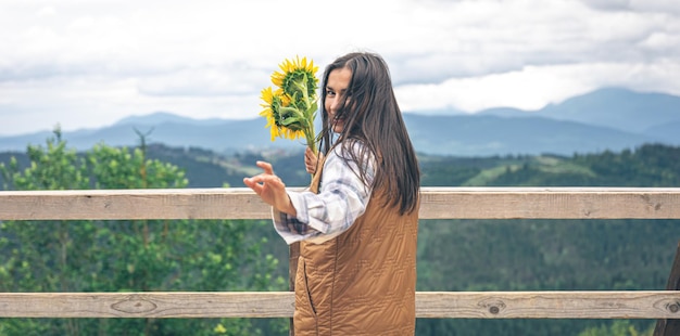 Mulher com um buquê de girassóis na natureza nas montanhas