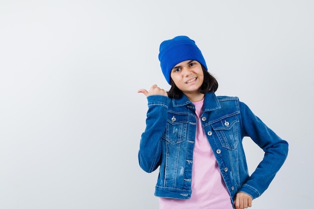 Foto grátis mulher com um gorro de jaqueta jeans de ganga apontando o polegar para cima