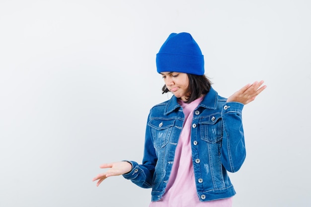 Mulher com um gorro de jaqueta jeans de ganga fazendo gesto de escamas parecendo hesitante