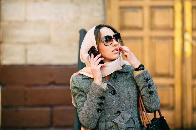 Mulher com um lenço rosa que fala no telefone