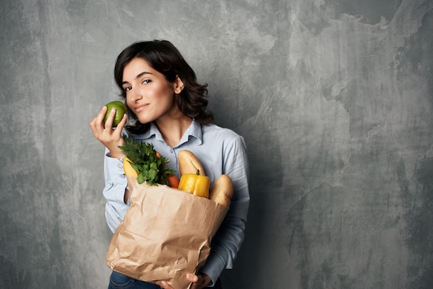 Mulher com um pacote de alimentos vegetais saudáveis alimentos fundo escuro