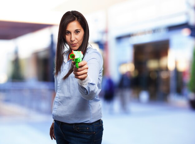 Mulher com uma arma de brinquedo verde