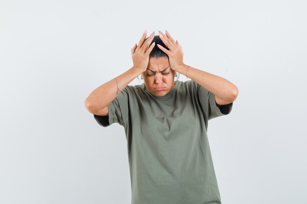 mulher com uma camiseta segurando as mãos na cabeça e parecendo triste