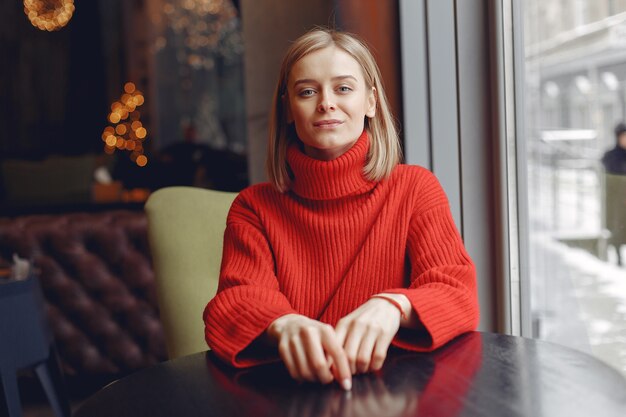 Mulher com uma camisola vermelha. Senhora em um restaurante.