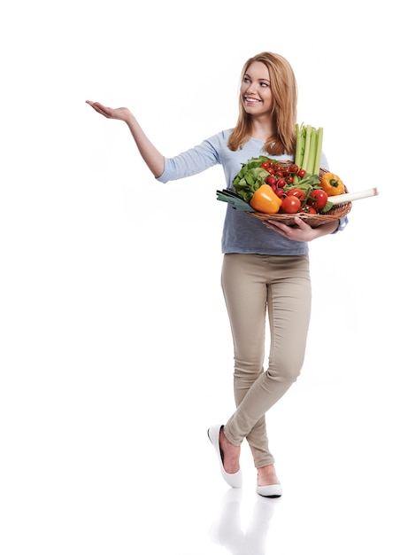 Foto grátis mulher com uma cesta cheia de alimentos saudáveis aparecendo no espaço da cópia