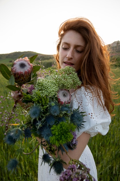 Foto grátis mulher com vista lateral de buquê de flores