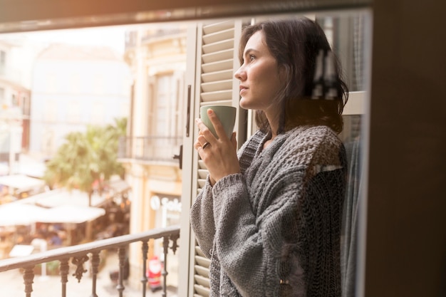 Mulher com vista lateral segurando uma xícara de café