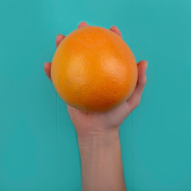 Foto grátis mulher com vista superior segurando a toranja em um fundo turquesa