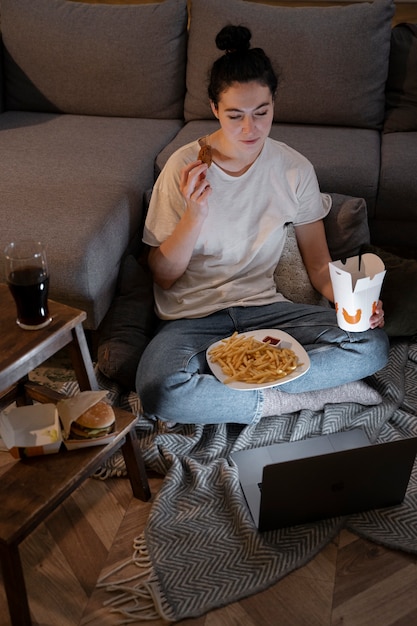 Mulher comendo fast food enquanto assiste a um filme